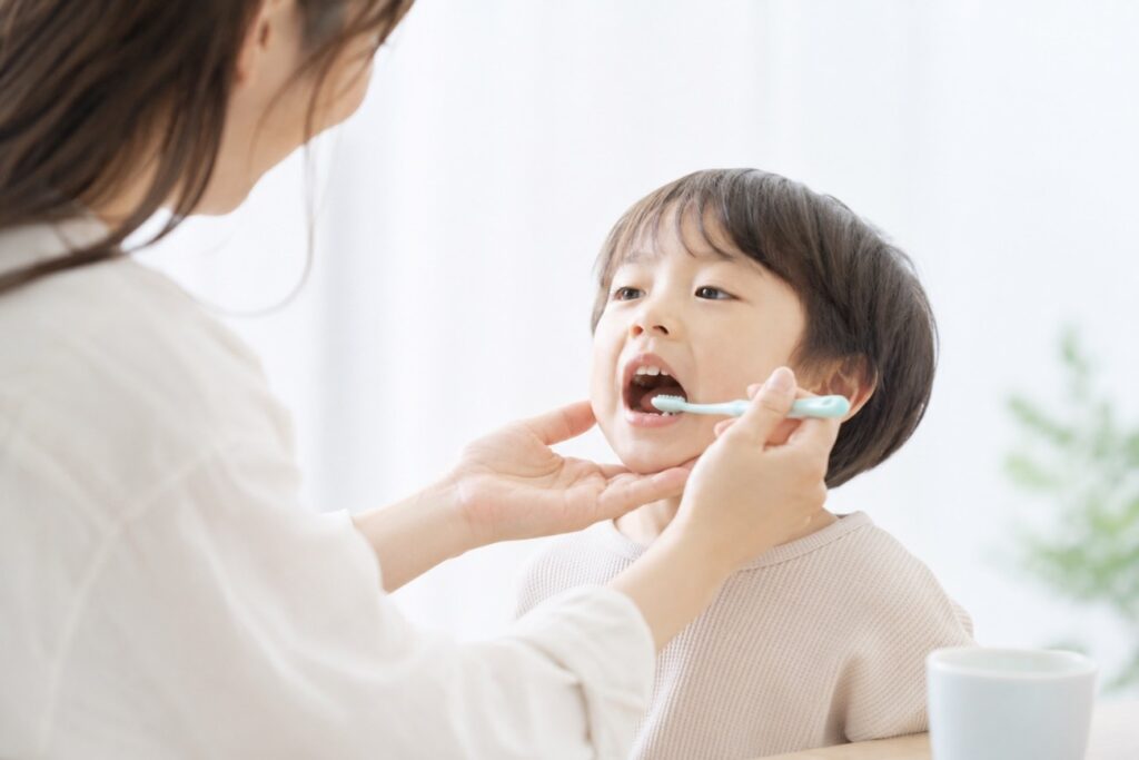男の子が母に仕上げ磨きをしてもらっている画像